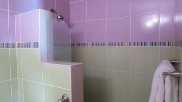 A bathroom with purple and green tiles, a glass shower enclosure, and a towel rack.