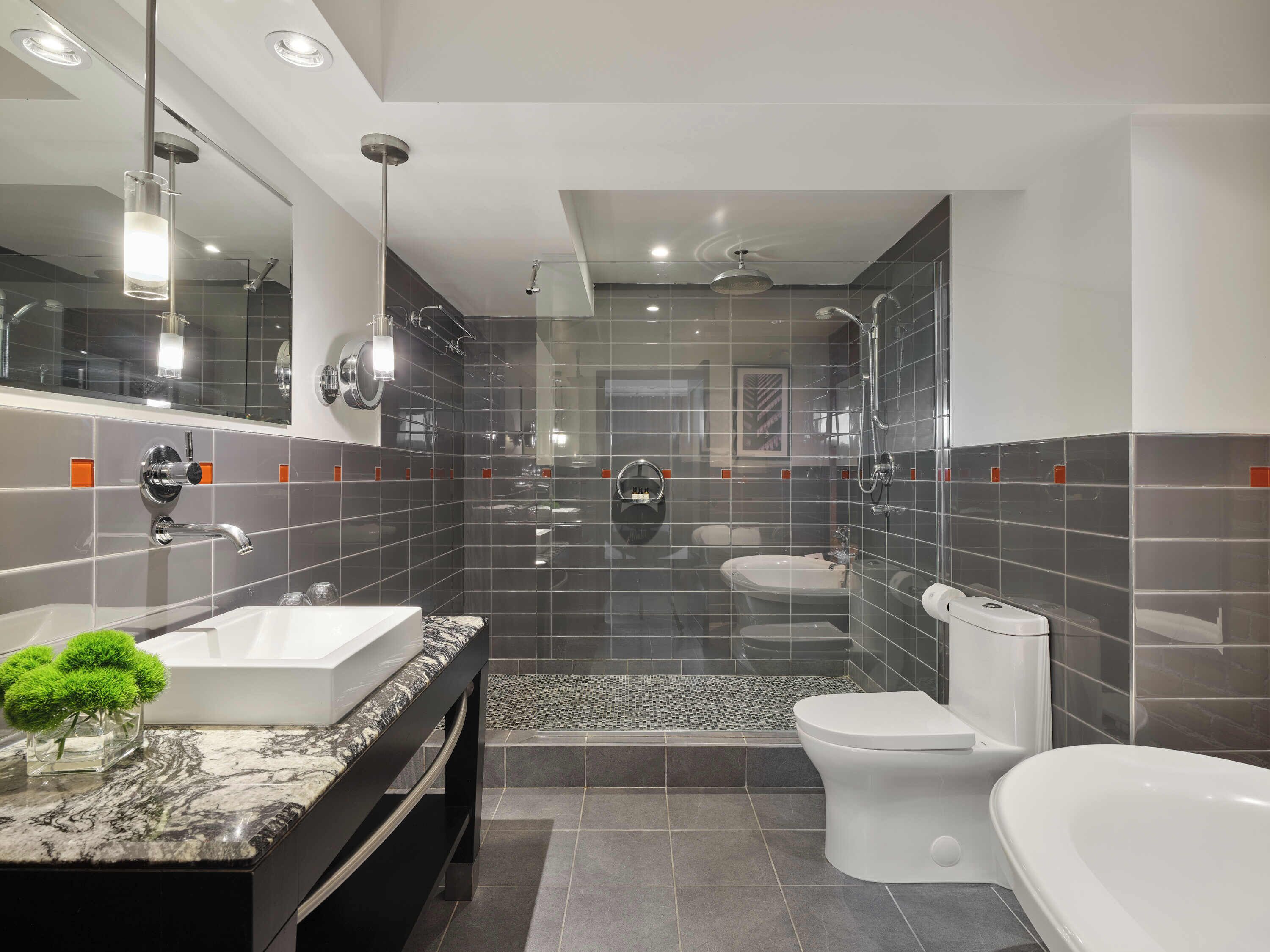 Een moderne badkamer met een grote spiegel, een wastafel, toilet en een douchegedeelte.