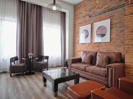 Una sala de estar moderna con un sofá de cuero, una mesa de centro y una pared de ladrillo decorada con dos obras de arte enmarcadas.