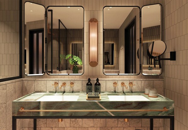 A bathroom with a marble sink, three mirrors, and a potted plant.