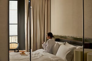 A hotel room with a bed, a chair, and a window with curtains.