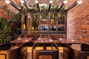 A restaurant with brick walls, hanging plants, and wooden furniture.