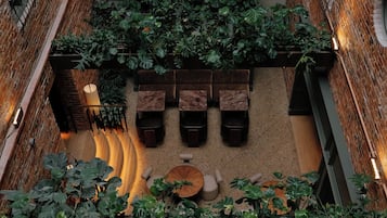 An indoor atrium with a curved wooden walkway, seating areas, and hanging plants.