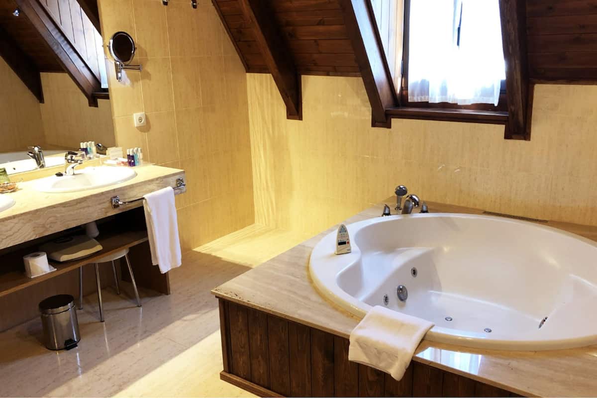 A bathroom with a wooden vanity, a large bathtub, and a mirror.