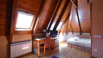 Un dormitorio acogedor en el ático con un escritorio de madera, una cama y un tragaluz.
