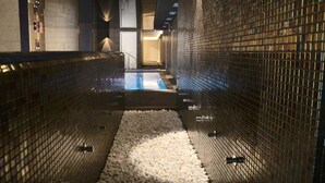 Un área de spa pequeña y cerrada con suelo y pared de azulejos, y una piscina.