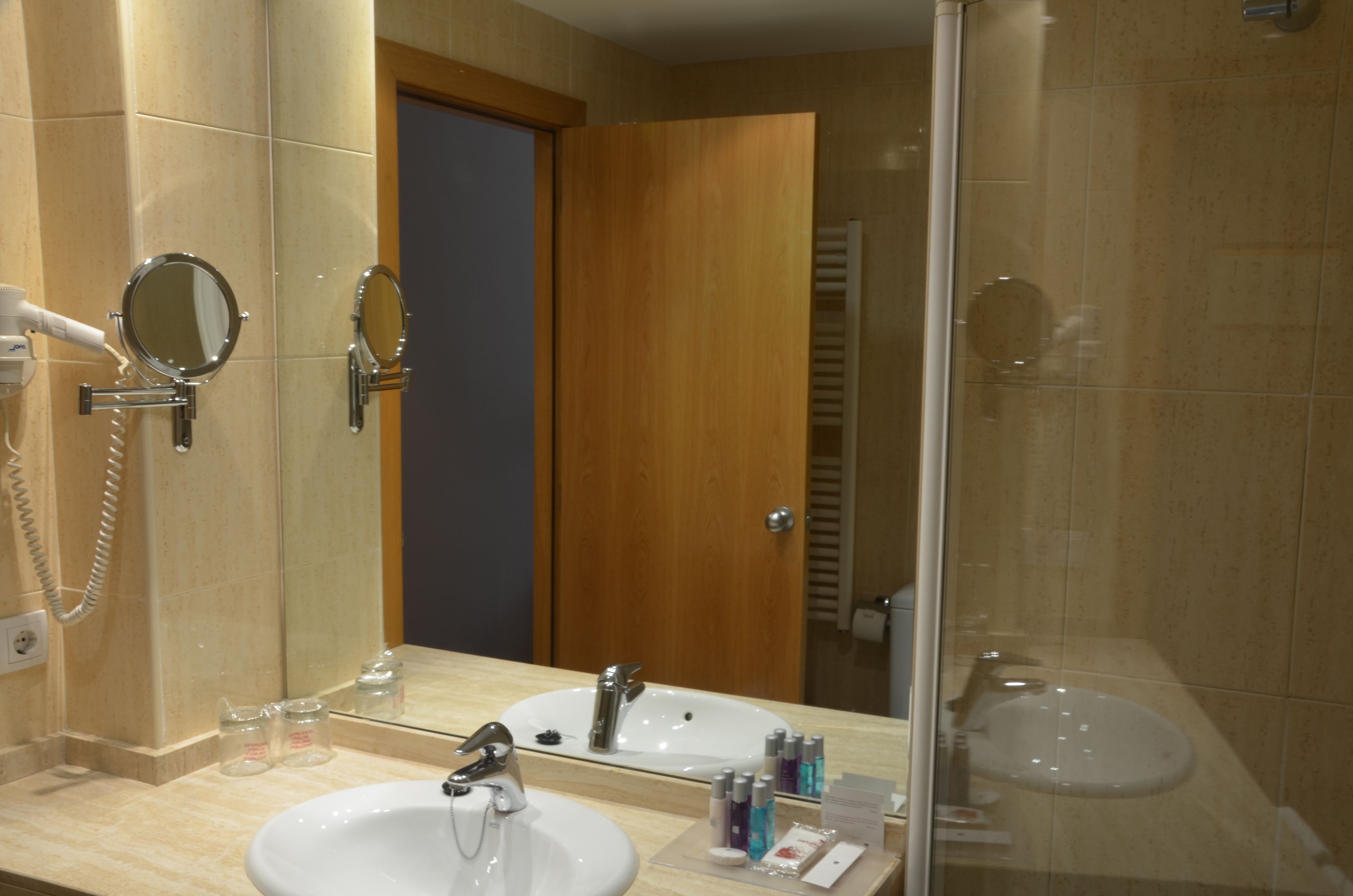 A bathroom with two sinks, a mirror, and a shower.