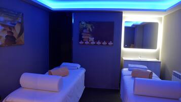 Un cuarto de spa con dos camas, un lavamanos y un espejo.
