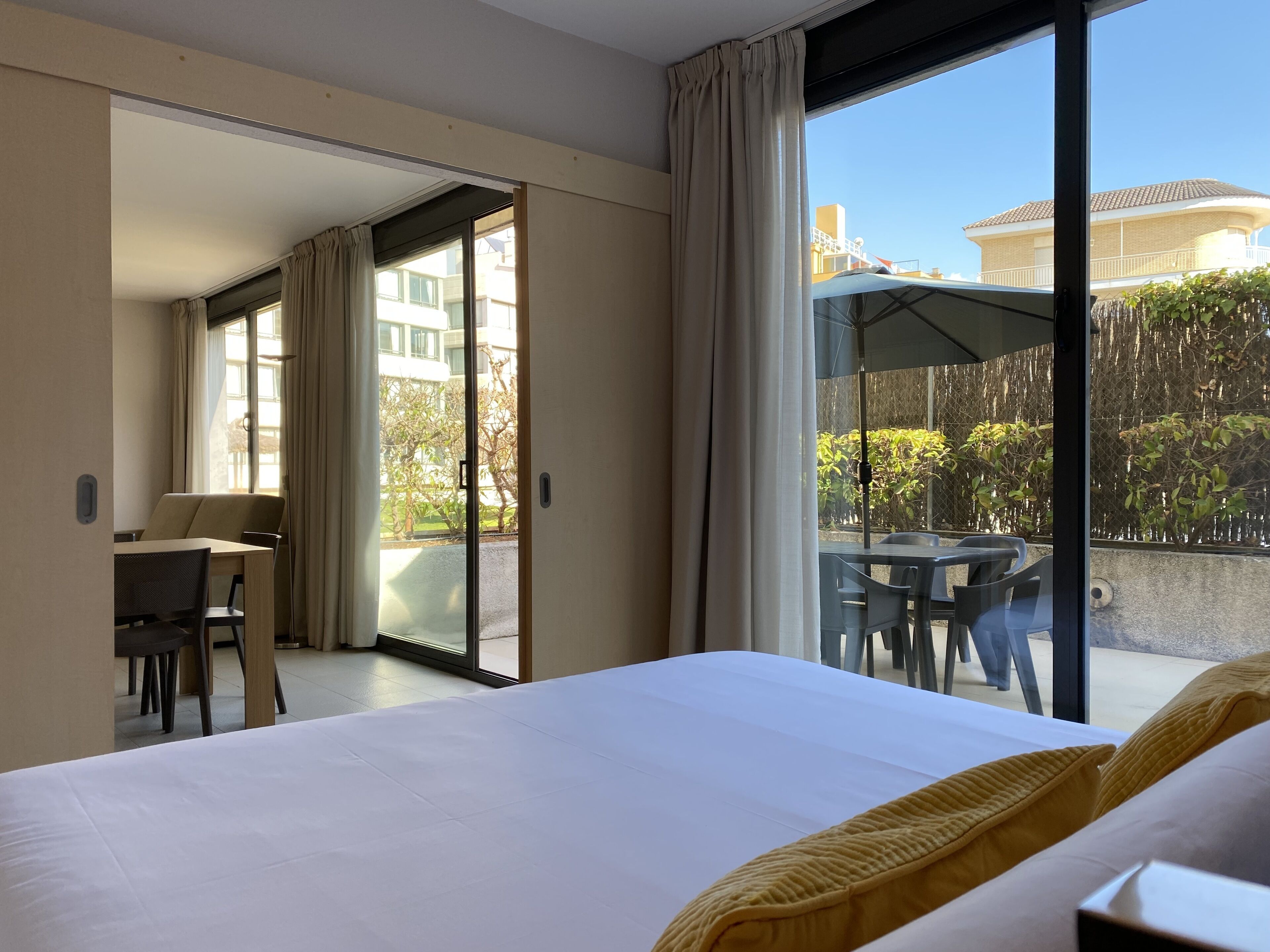 A hotel room with a large bed, a desk, and a balcony with a table and chairs.