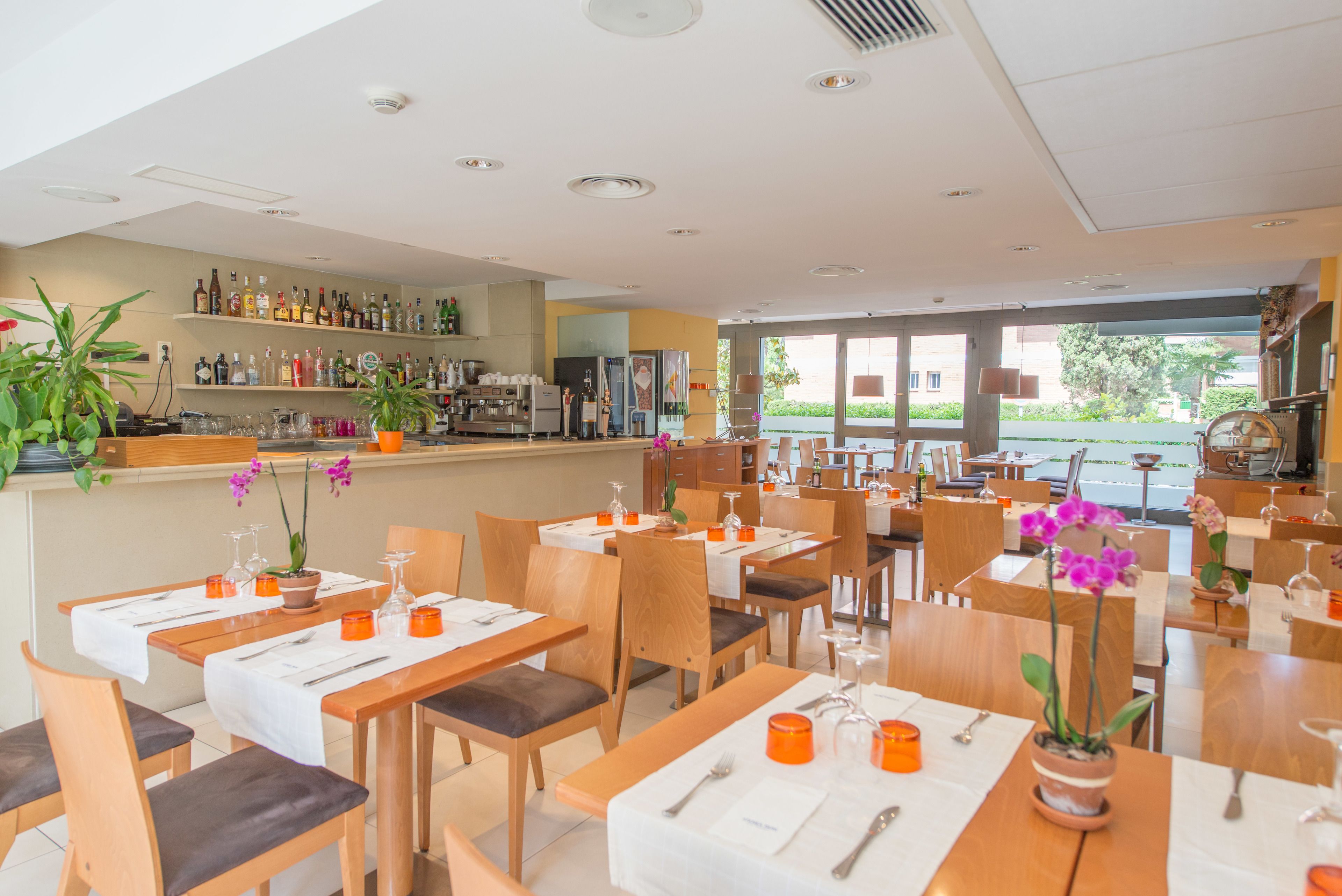 A restaurant with multiple tables, chairs, and potted plants.