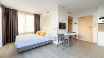 A hotel room with a bed, a desk with a chair, a TV, and a door.