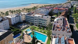 Un hotel con piscina en la azotea, vista al mar y un paisaje urbano de fondo.