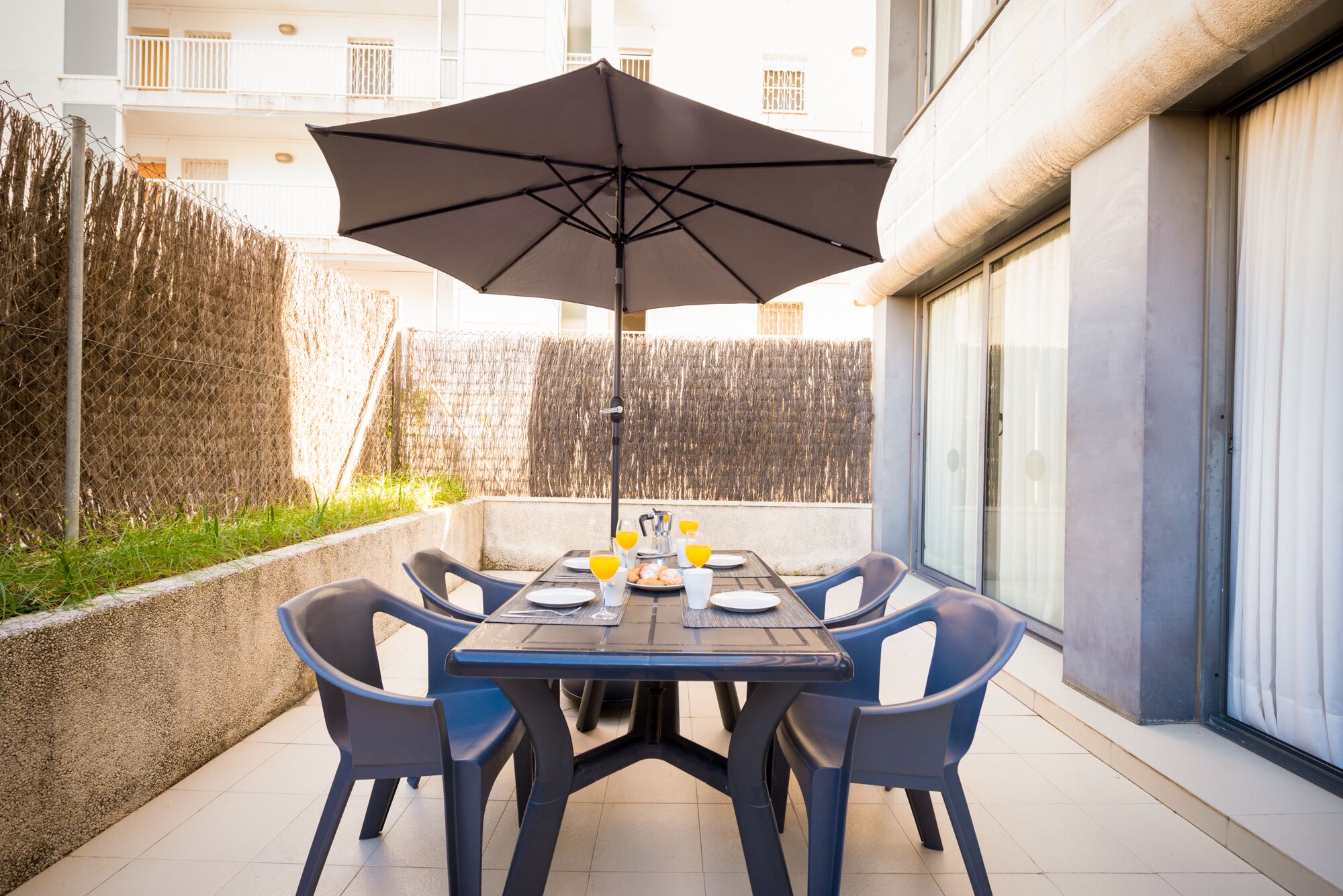 Une terrasse avec une table mise pour le petit-déjeuner, comprenant des assiettes, des verres et une cafetière.