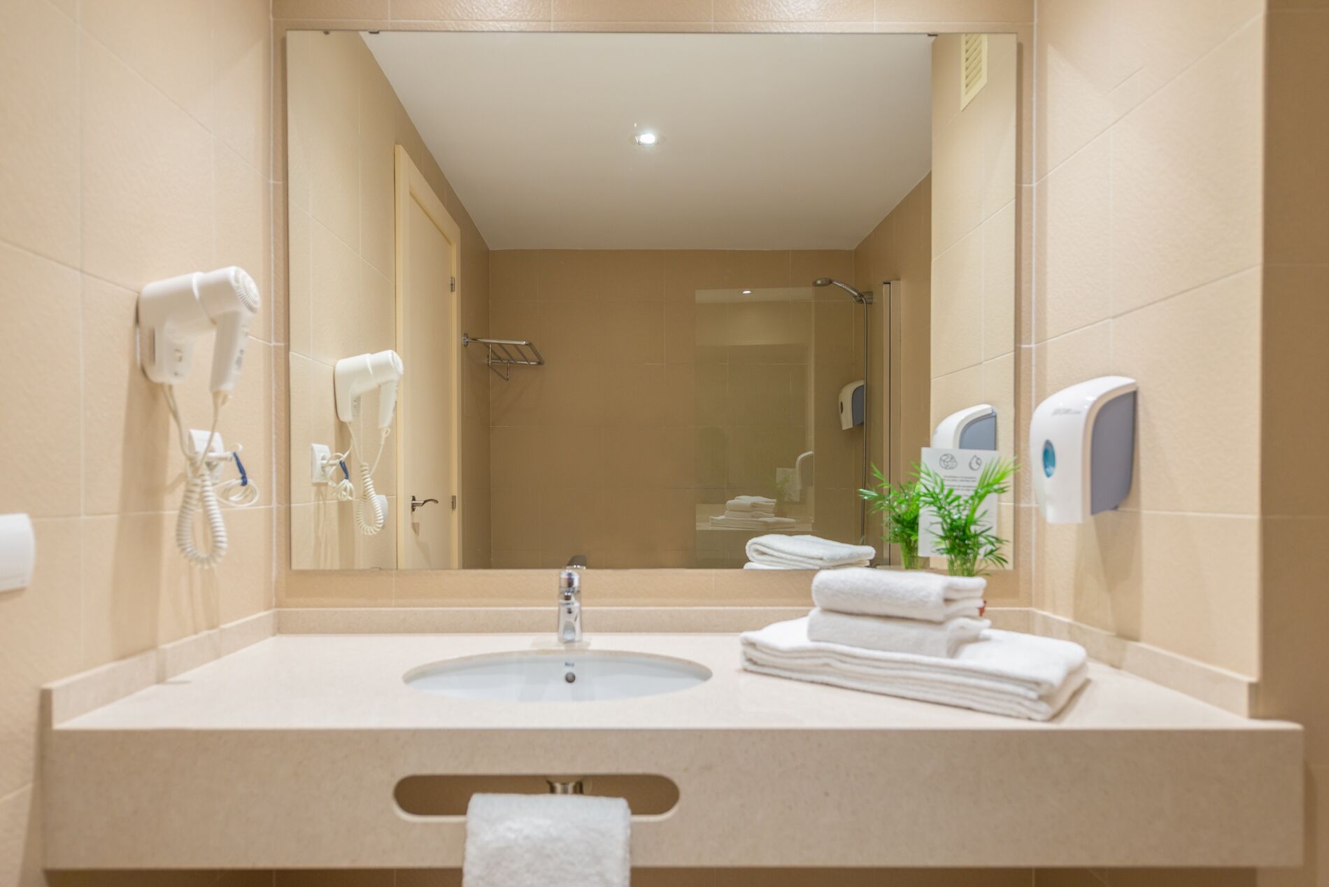 Un baño moderno con lavabo, toallero, secador de pelo y secamanos.