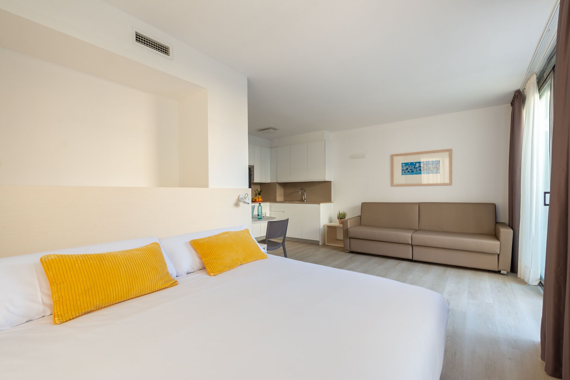 Een hotelkamer met een bed, een bank, een bureau en een kitchenette.