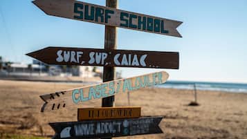 A wooden signpost with multiple directional signs, including one labeled "SURF SCHOOL".