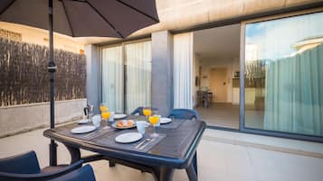 Un comedor con una mesa dispuesta para dos personas, incluyendo platos, cubiertos y vasos de jugo de naranja.