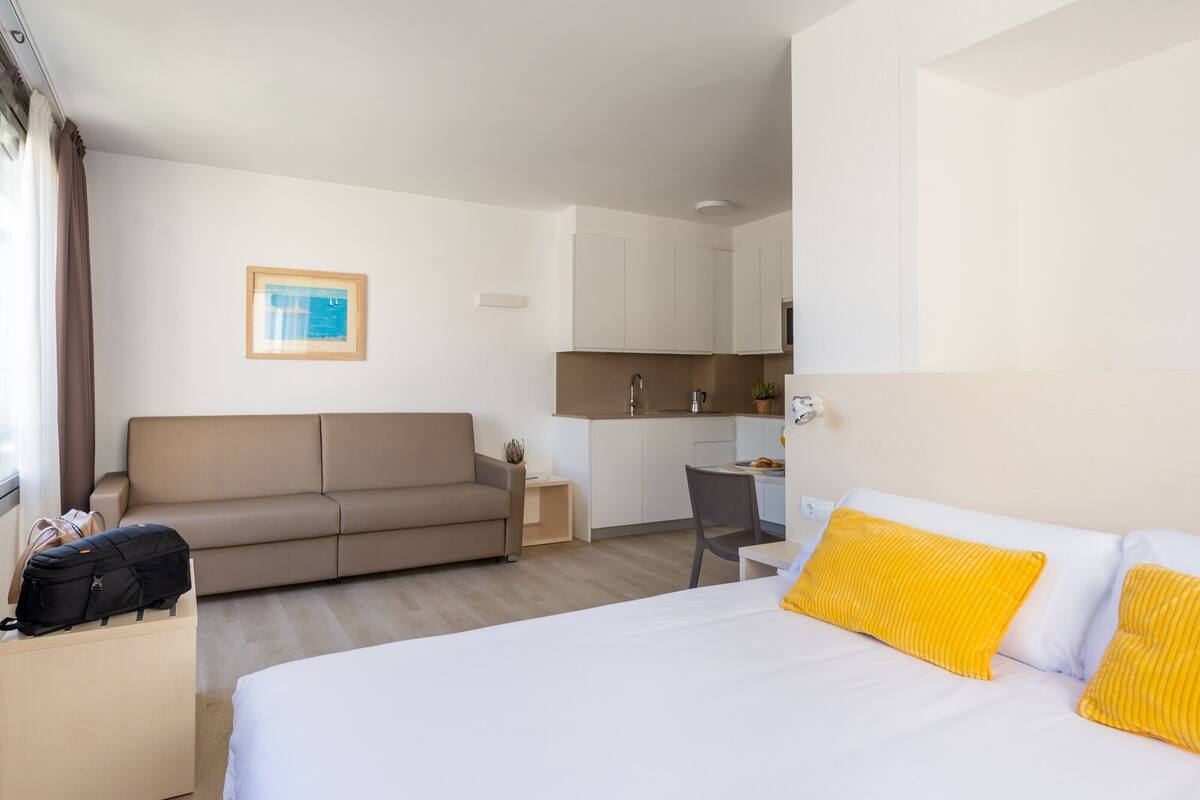 Una habitación de hotel con cama, sofá, escritorio y kitchenette.
