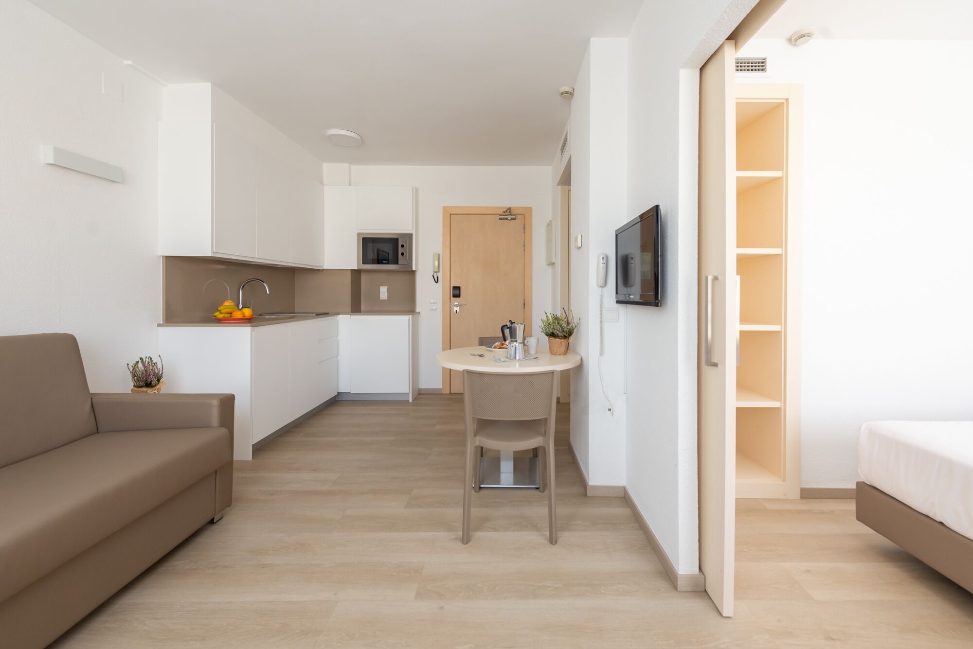A modern apartment with a kitchenette, a dining area, a living room, and a bedroom.