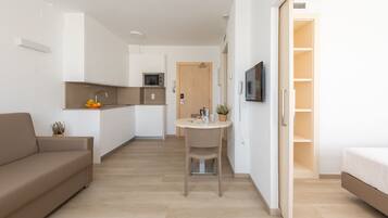 A modern apartment with a kitchenette, a dining area, a living room, and a bedroom.
