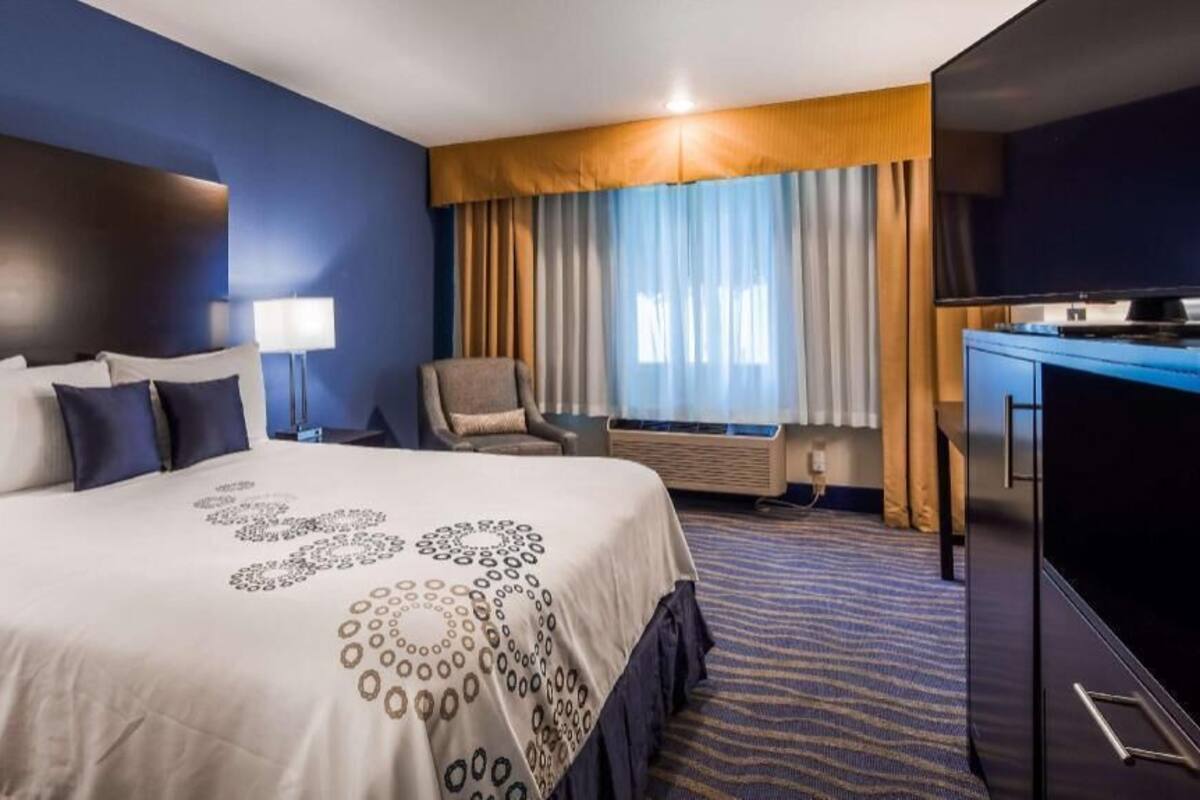A hotel room with a large bed, a desk, a chair, and a TV.
