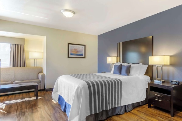 A hotel room with a large bed, bedside tables, a sofa, and a painting on the wall.