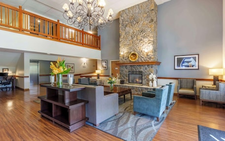 A spacious lobby with a fireplace, comfortable seating, a reception desk, and a staircase.