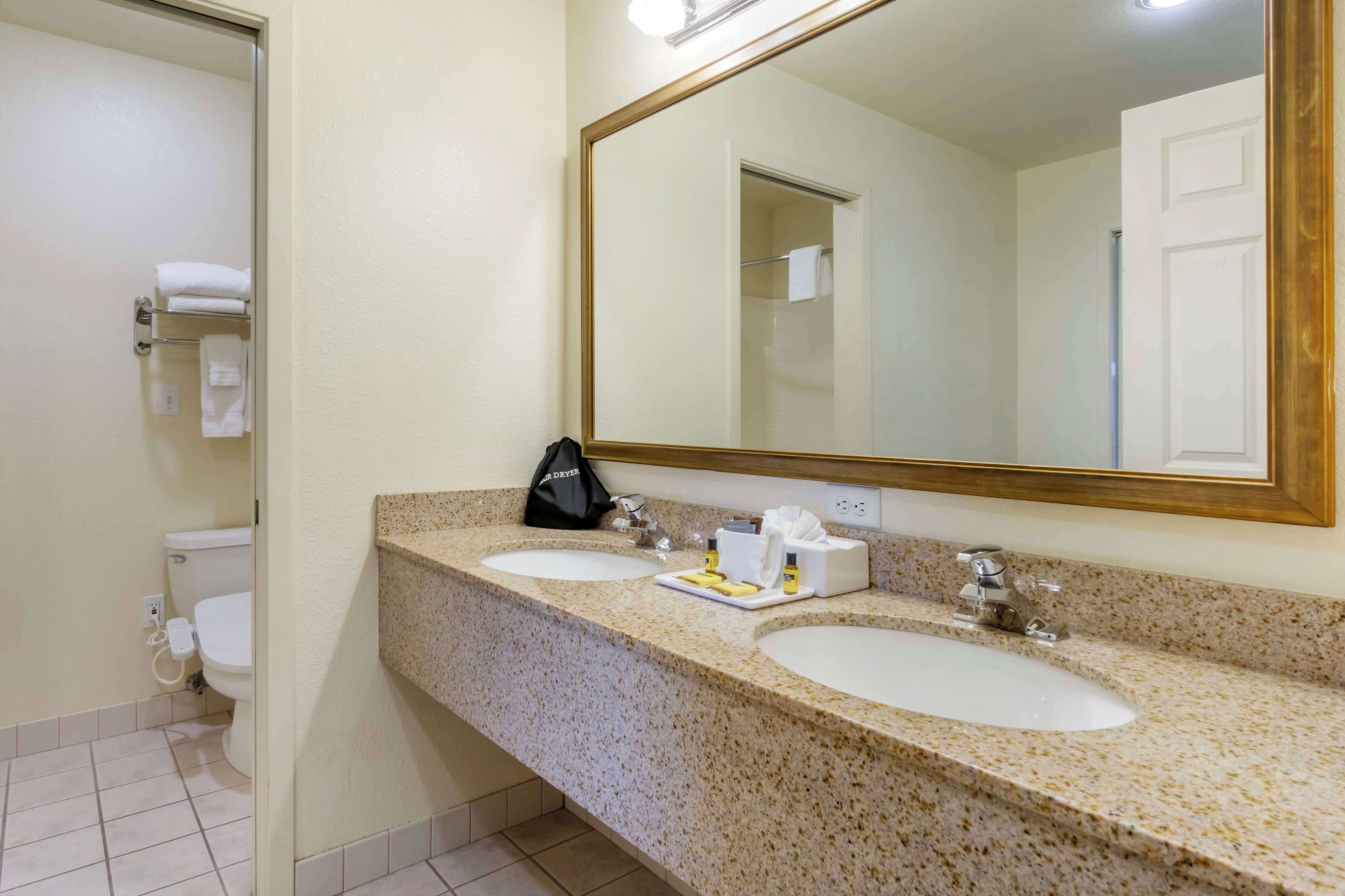 A bathroom with two sinks, a large mirror, and a toilet.