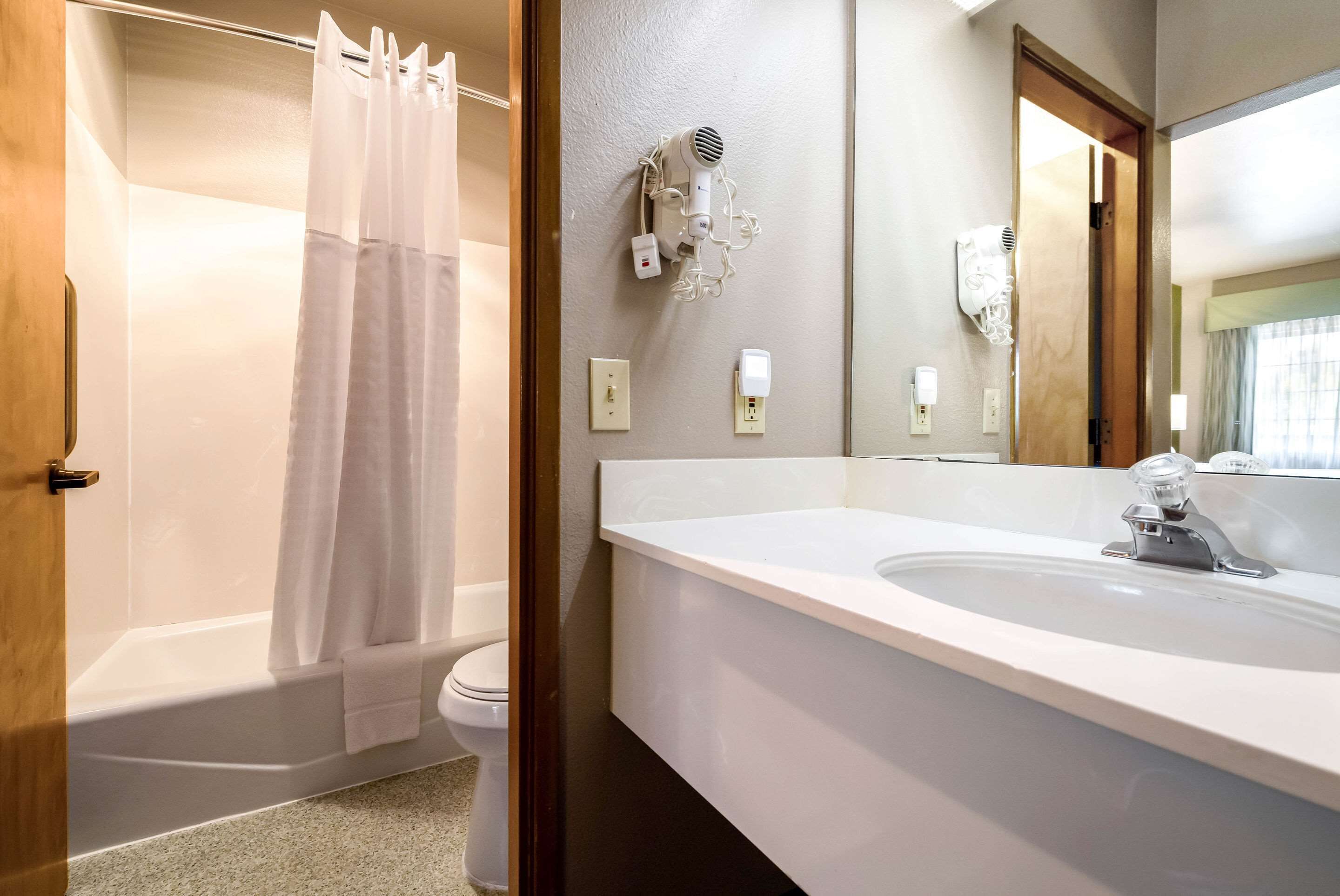 Un baño con ducha, inodoro y lavamanos con espejo.