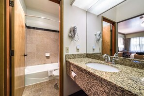 A hotel bathroom with a granite countertop sink, a bathtub, and a mirror. - Quality Inn & Suites Bainbridge Island (Bainbridge Island)