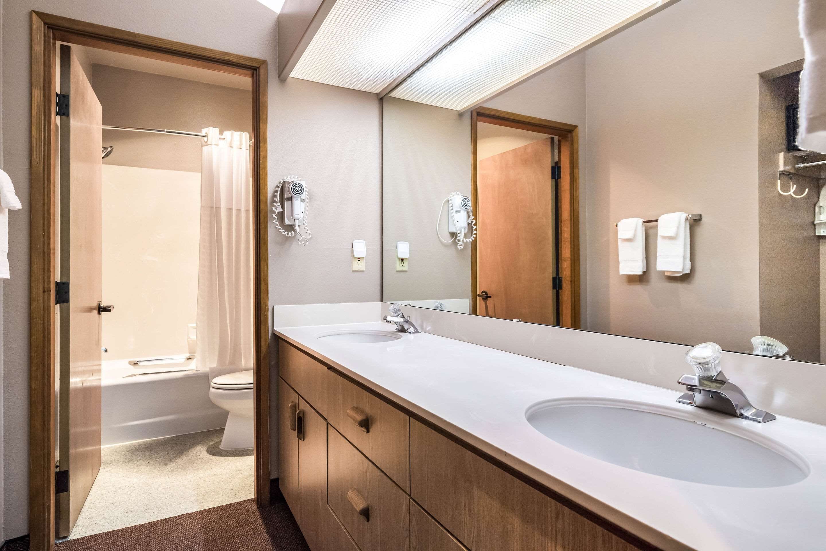 A modern bathroom with a double sink, a large mirror, and a shower area.