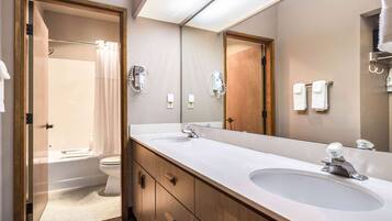 A modern bathroom with a double sink, a large mirror, and a shower area.