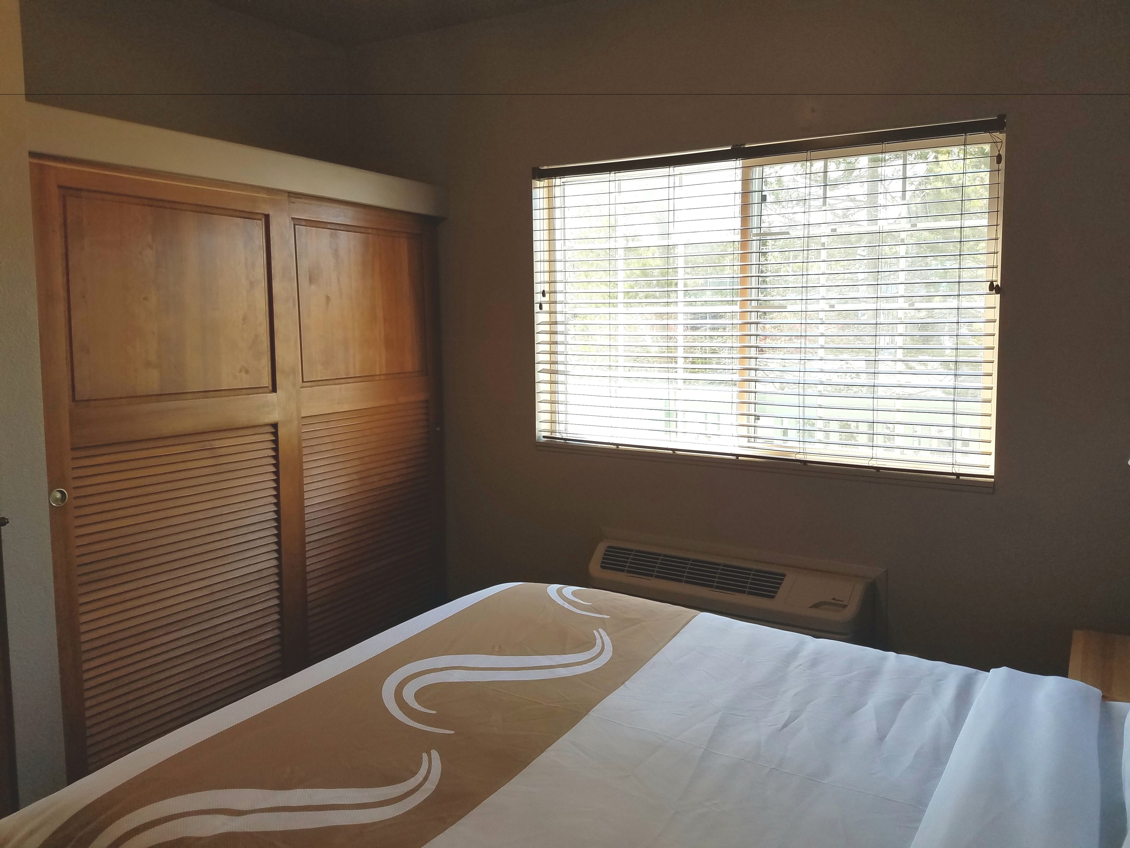 Un dormitorio con una cama, una ventana con persianas, un armario y un radiador.