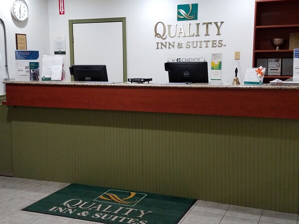 A reception desk with a sign reading "QUALITY INN & SUITES."