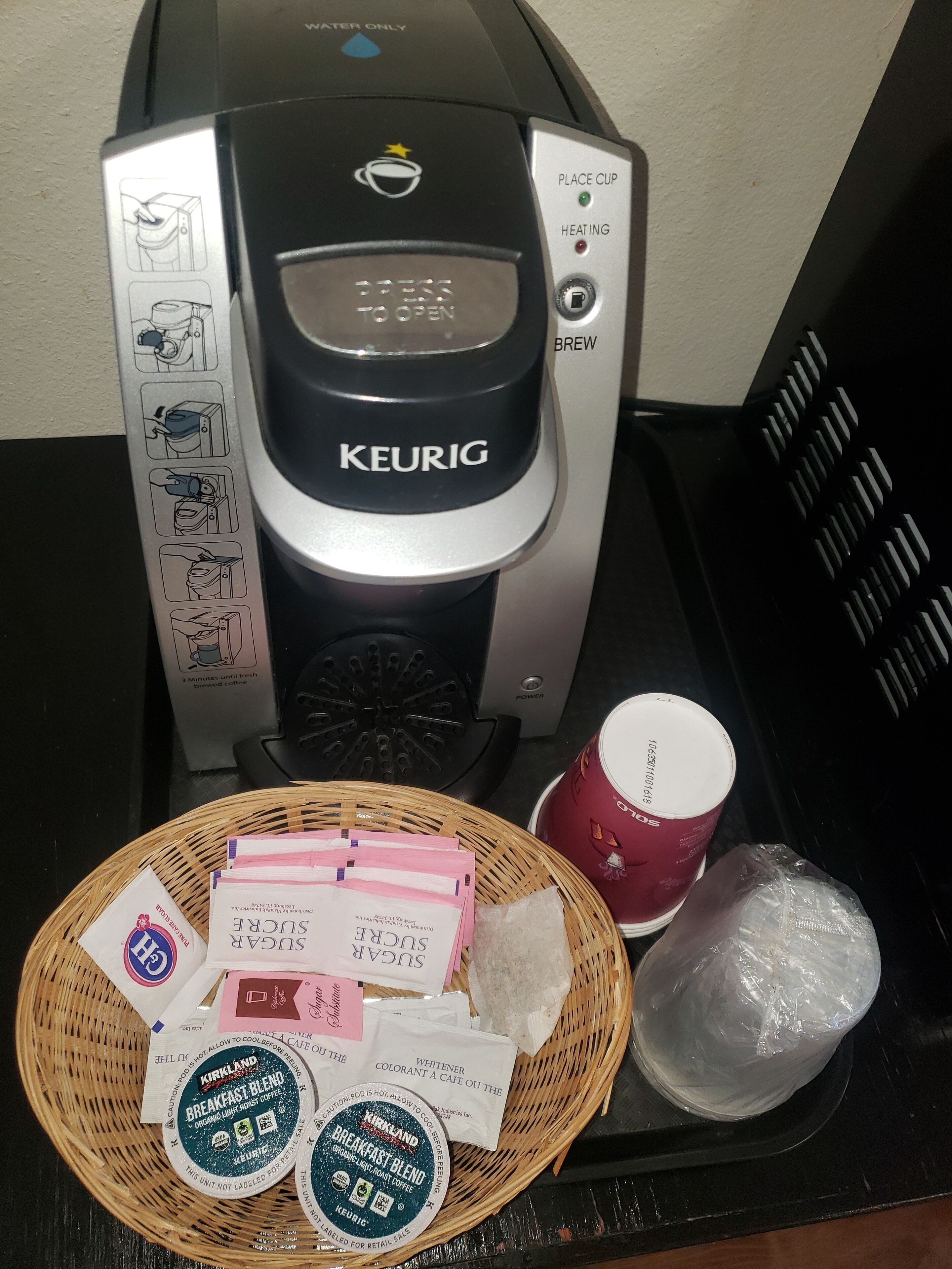 A Keurig coffee maker with a basket of coffee pods and a mug on a countertop.