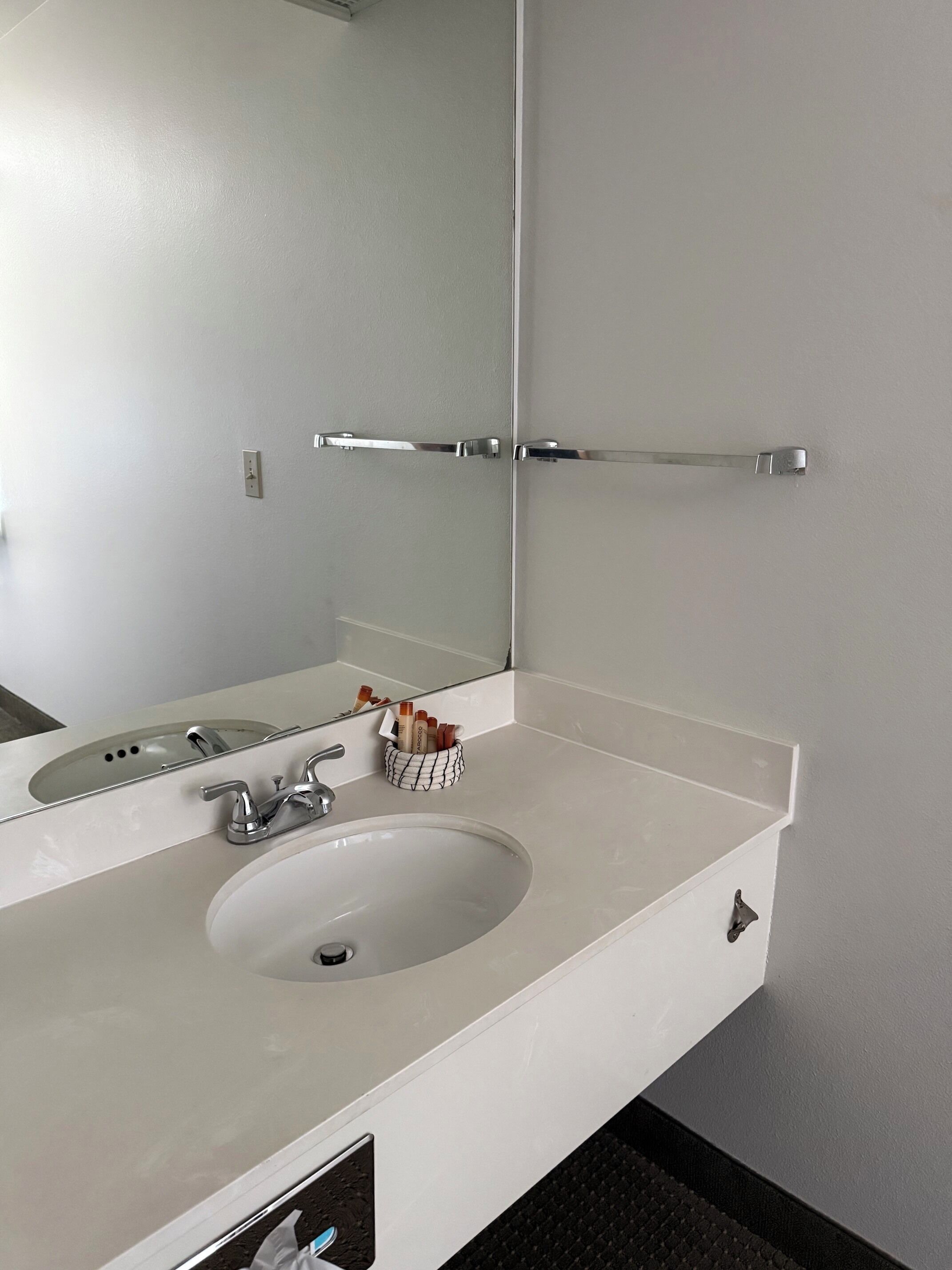 Un bagno con un lavandino bianco, uno specchio e un portascopevoli.