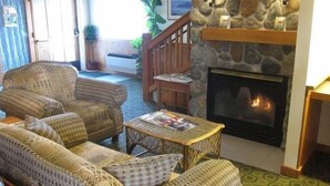 A cozy living room with wicker furniture, a fireplace, and a staircase leading to another level. - Fidalgo Country Inn (Anacortes)