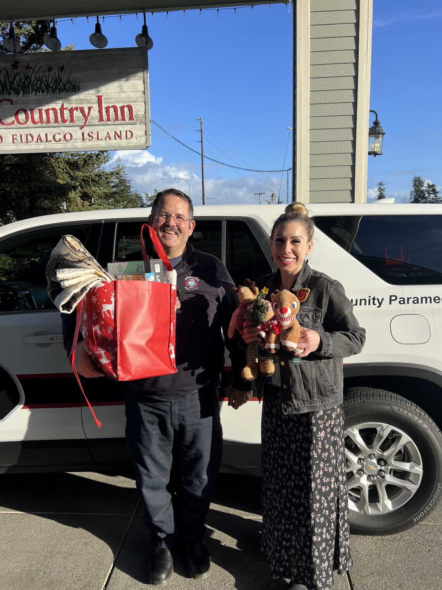 Two people holding gifts in front of a Country Inn sign.