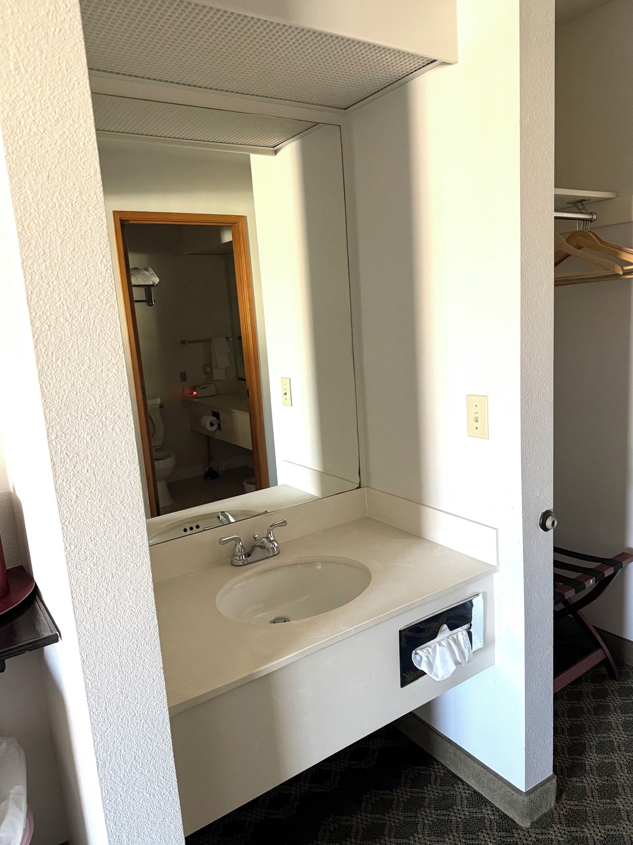 A bathroom with a white sink, mirror, and towel rack.