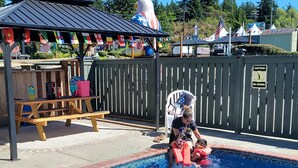 A swimming pool with a wooden deck, picnic tables, and a covered seating area. - Fidalgo Country Inn (Anacortes)