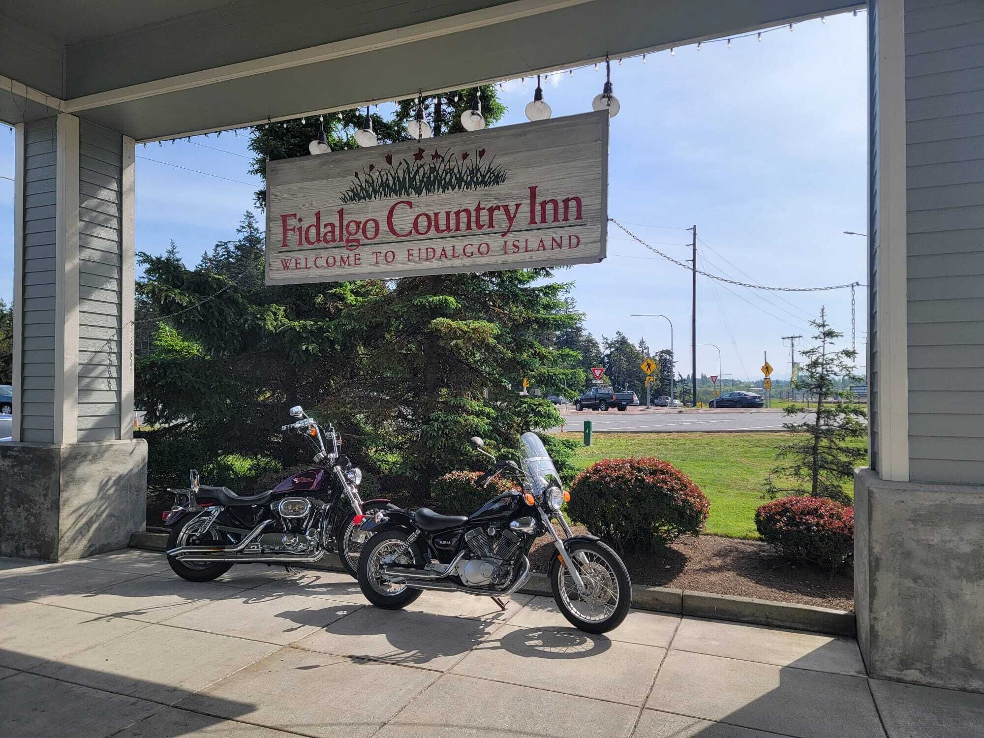 A sign for Fidalgo Country Inn welcoming to Fidalgo Island, with motorcycles parked in front.