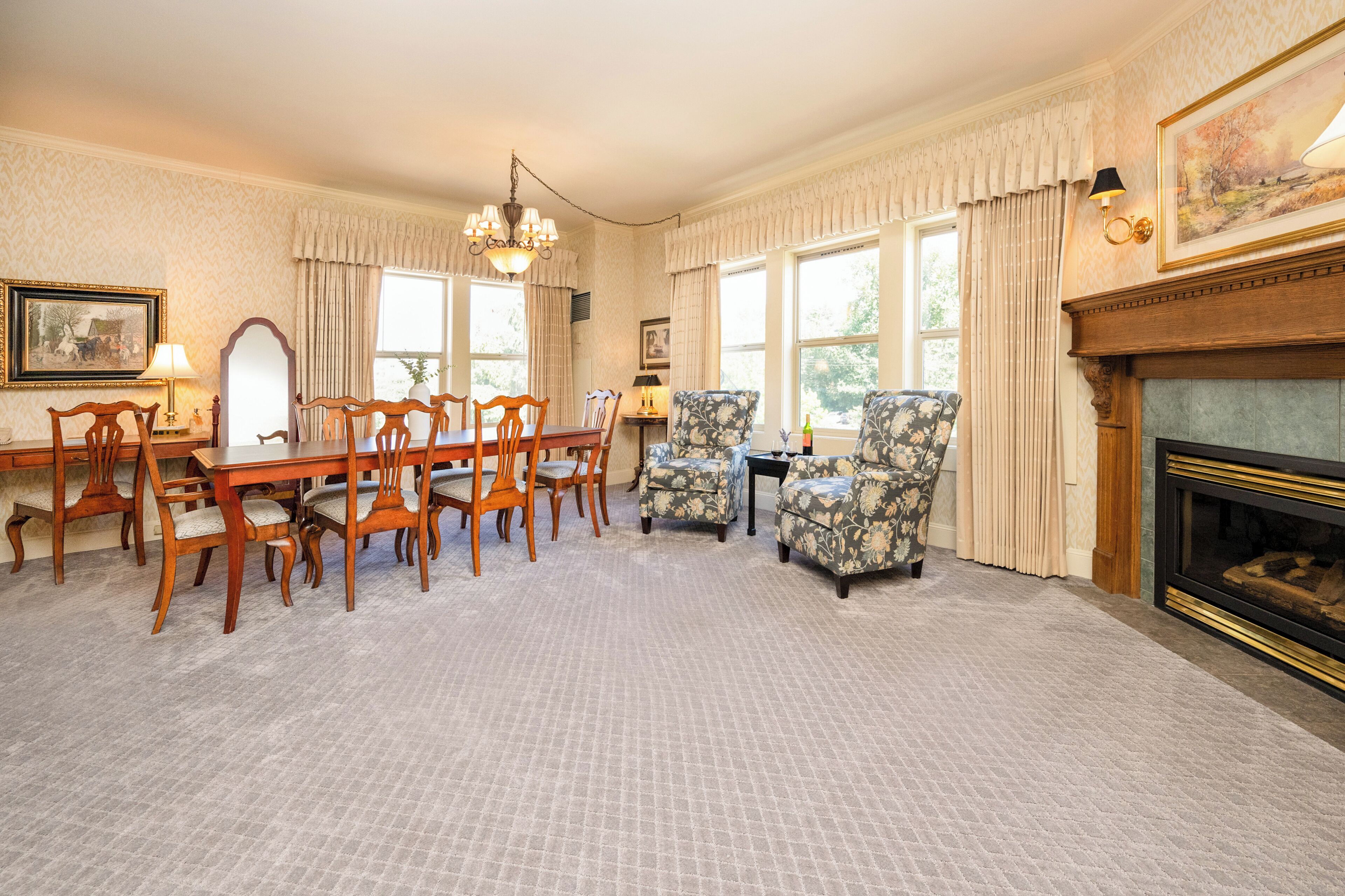 A spacious room with a dining table, chairs, a fireplace, and large windows.