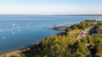 Eine Küstenlandschaft mit einer Pier, die sich ins Wasser erstreckt, umgeben von Grünflächen und einem Parkplatz.
