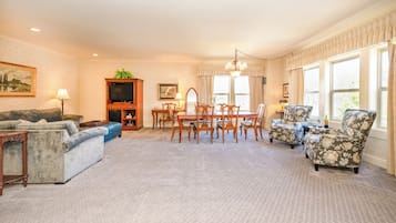 Un salón amplio con un sofá, sillones, una mesa de comedor y una televisión.
