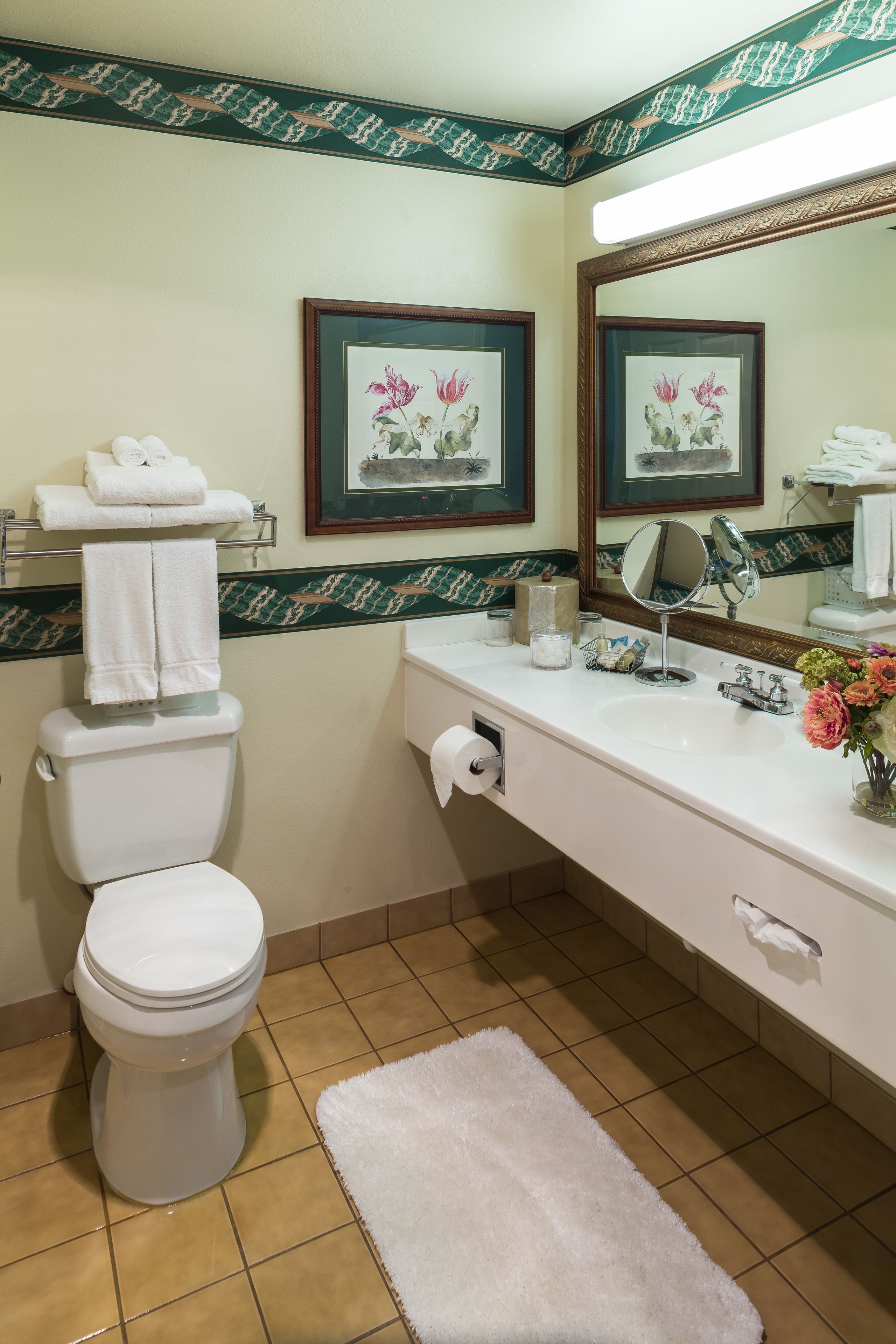 Une salle de bain avec des toilettes, un lavabo et un miroir. Il y a des serviettes sur les toilettes et un rouleau de papier toilette sur le comptoir.