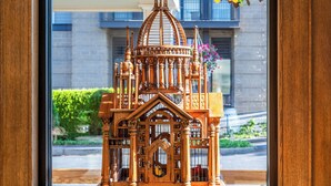 A wooden model of a church on a table in front of a window with a view of a building and greenery outside. - Fairhaven Village Inn (Bellingham)