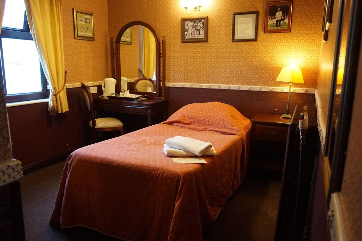 A hotel room with a bed, a dresser, a mirror, a lamp, and a window with curtains.