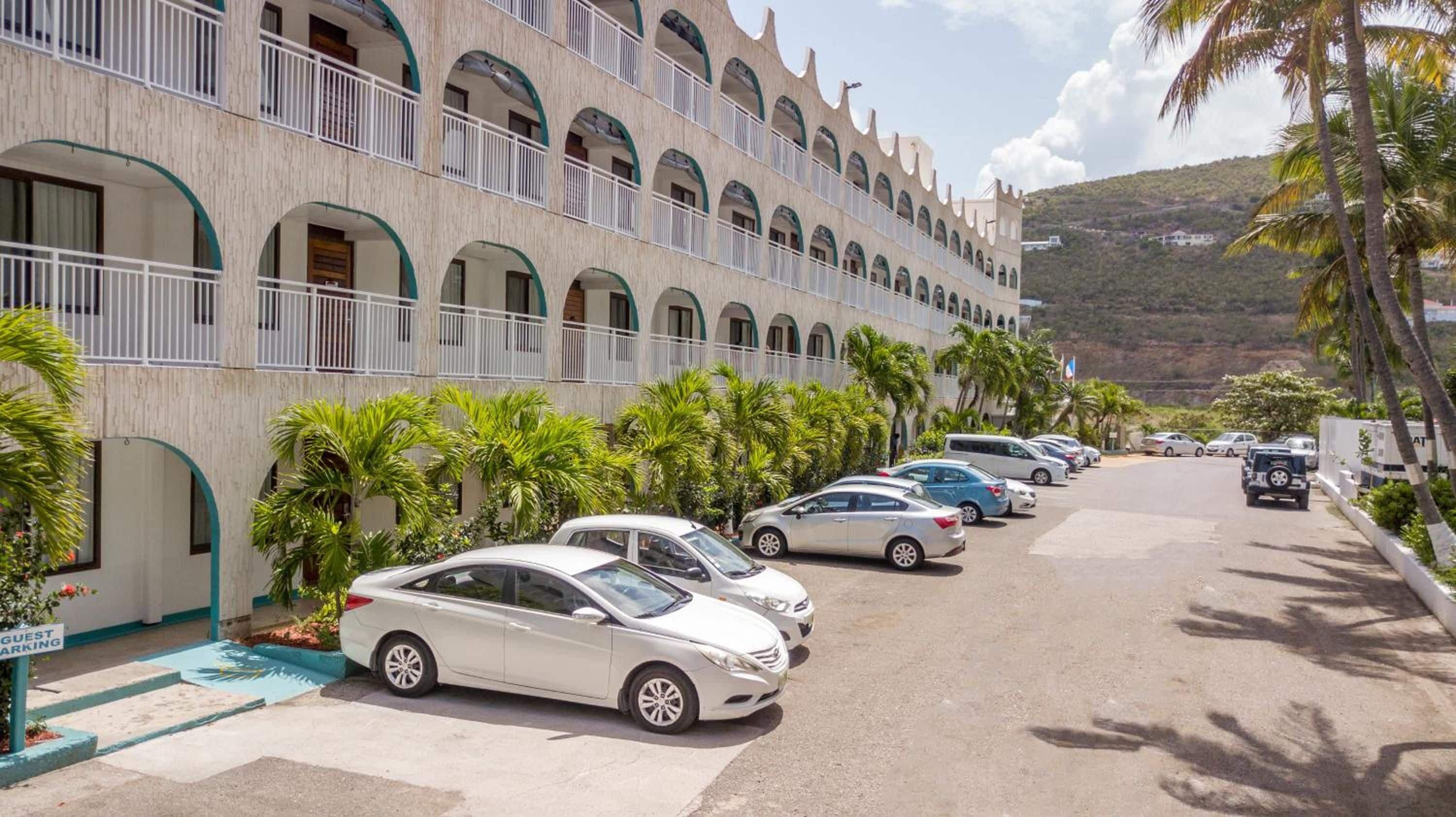 Un hôtel avec une rangée de voitures garées et un espace piscine.