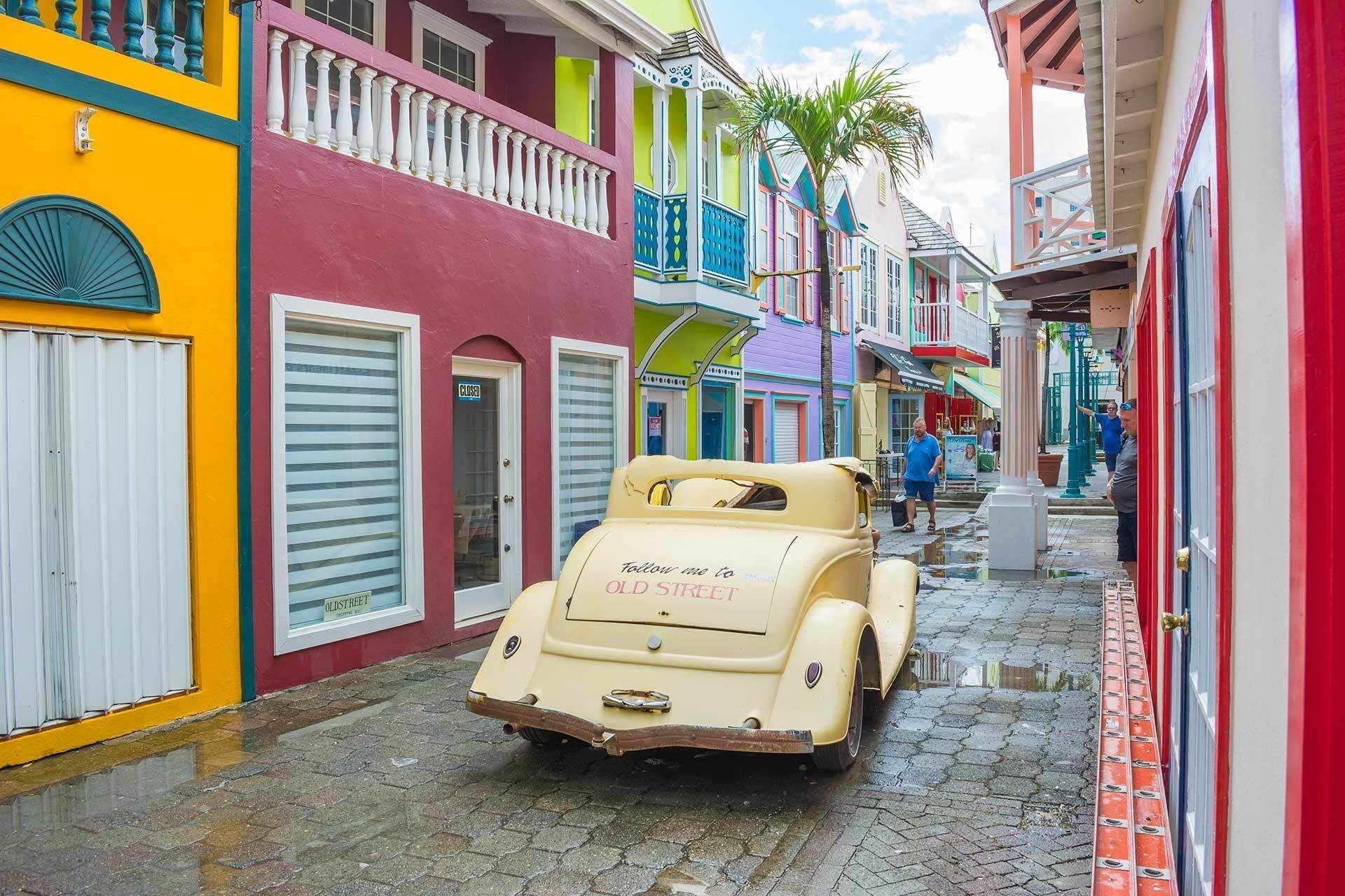 Un coche antiguo estacionado en una calle adoquinada flanqueada por edificios coloridos.