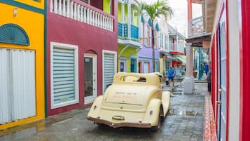Un coche antiguo estacionado en una calle adoquinada flanqueada por edificios coloridos.